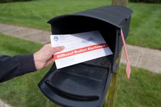Man depositing an official ballot into a mailbox