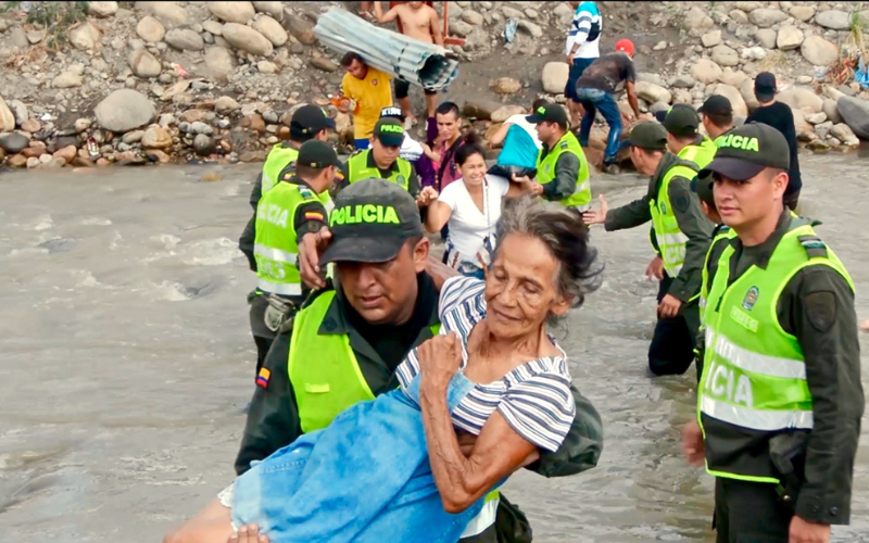 Una anciana refugiada venezolana siendo transportada por la Policía Nacional de Colombia a través del río Táchira desde Venezuela hacia Colombia. Crédito de la imagen: Wikimedia, 2015.