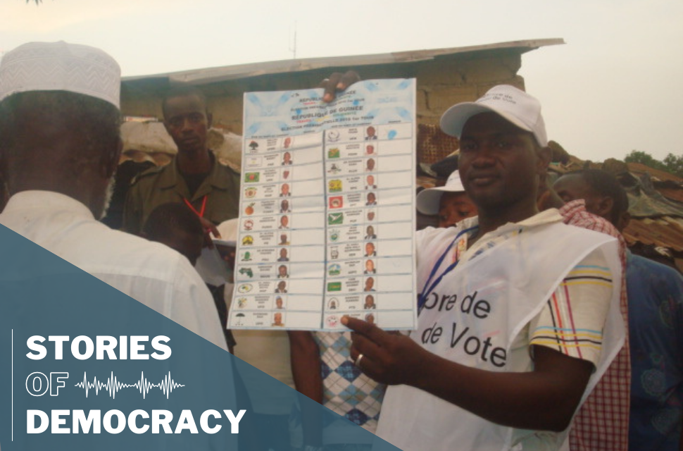 Polling worker showing voters the ballot for the election in Guinea.