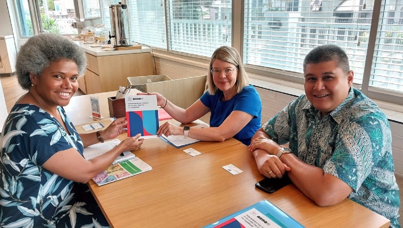 three persons sitting at table displaying publications