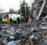 Rescure team members stands behind a collappsed bulding after eathquake
