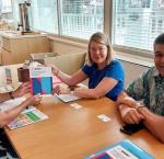 three persons sitting at table displaying publications